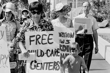 a woman holds a sign that reads ‘free childcare centers’