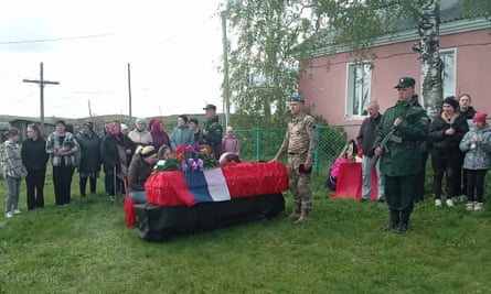 People stand solemnly near a casket