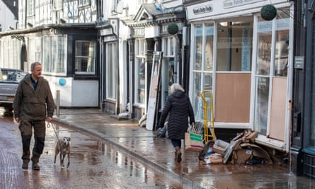 People walk past boarded-up shop with pile of rubbish outside