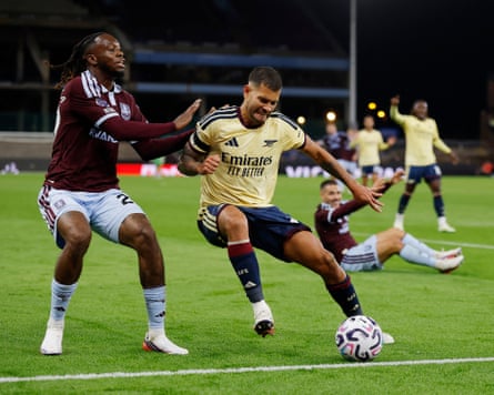 The Arsenal midfielder Bruno Guimarães (right) shields the ball under pressure from the Aston Villa defender Aaron Wan-Bissaka (left).