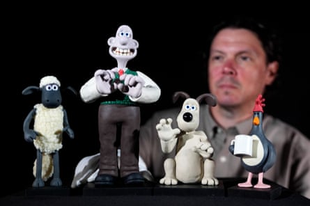 A man stands next to figurines of Shaun the Sheep, Wallace, Gromit and Feathers McGraw.