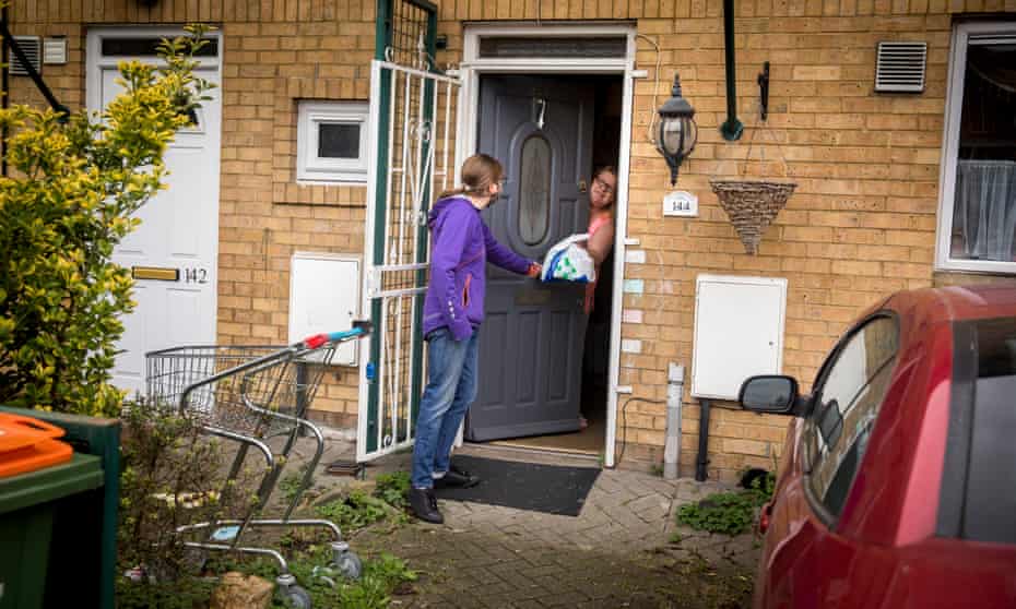 Isobel, Michael and their dog Bowie in Newham, receive their prescription from volunteer Hilary Wood.