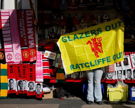A Manchester United merchandise seller displays a flag that says Glazers Out Ratcliffe Out