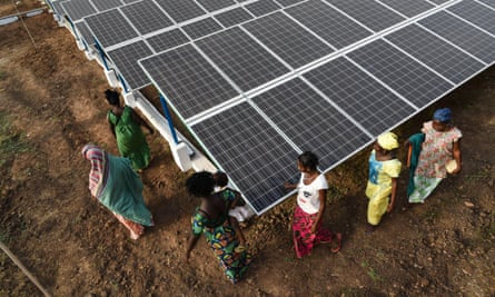 Women standing beside solar panels.