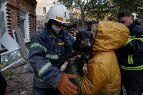 A rescuer gives a dog to a local woman at the site of a badly damaged home.