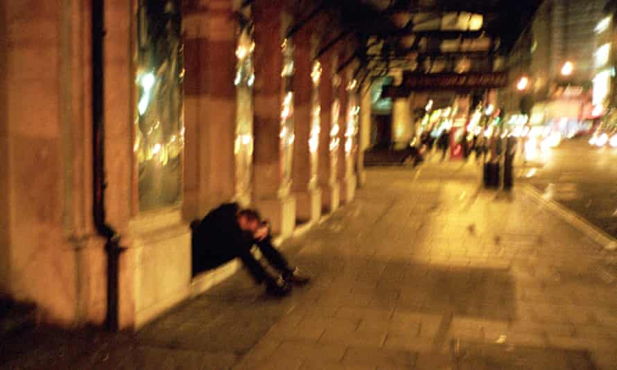 Man with head in hands in the street, Soho, London