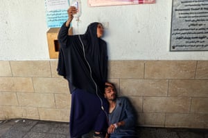 A Palestinian woman holds an intravenous drip for an injured man outside al-Najjar hospital in Rafah, Gaza following Israeli bombardment