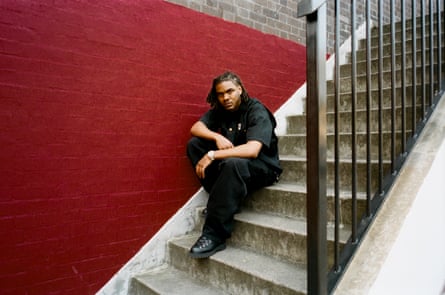 Pozer looks pensively at the camera, sat on a set of concrete stairs