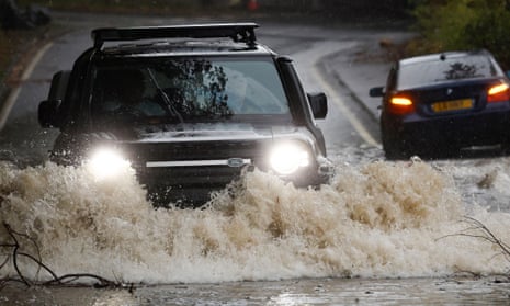 A car drives through flood water as torrential rain continues in Dumbarton, Scotland.