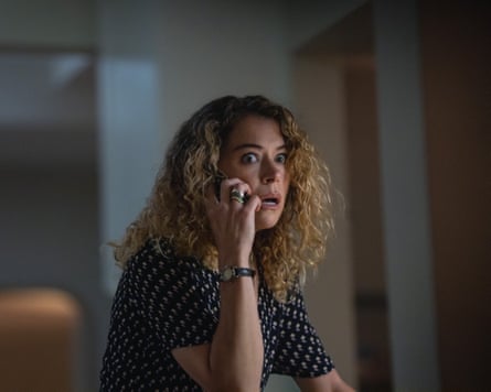 Scared looking white woman holds a phone to her ear.