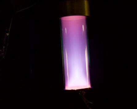 A glass tube used to recreate cosmic dust in the laboratory. It glows with purple and pink light