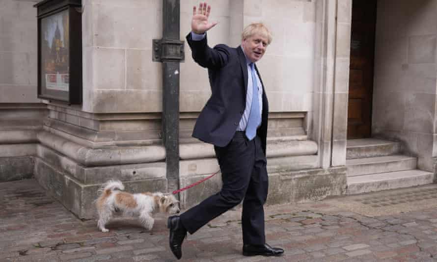 British Prime Minister Boris Johnson waves to the media with his dog Dilyn after casting his vote at a polling station on Thursday