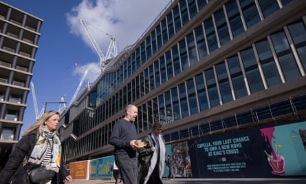 People walk past a extremely long, low glass-and-concrete building