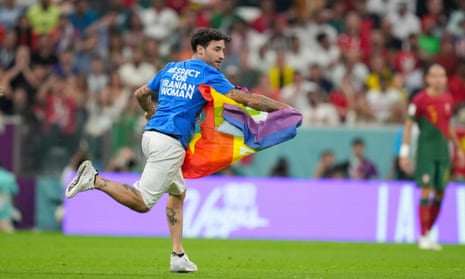 A pitch invader runs across the field with a rainbow flag.