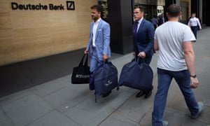 The tailors Alex Riley, left, and Ian Fielding-Calcutt carry suit bags outside the Deutsche Bank building in the City of London.