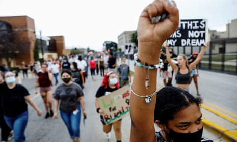 A woman reacts with a raised fist while marching with others, following the police shooting of Jacob Blake, a Black man, in Kenosha, Wisconsin, on Friday.
