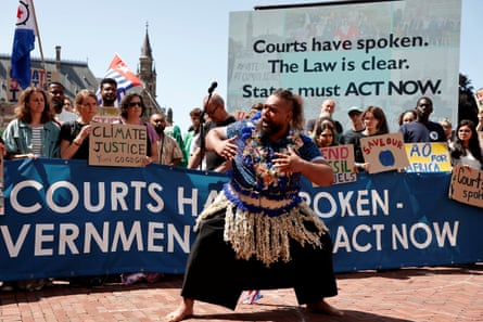 banners read 'courts have spoken. The law is clear. States must act now' and people hold signs including 'end fossil fuels', 'climate justice' and 'law of the sea court said protect the ocean'. A man is dancing; he looks as if he is a Pacific islander in traditional costume.