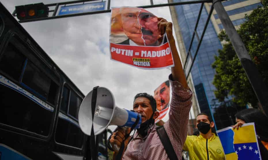 An opposition party activist holds a placard showing the face of Vladimir Putin and Nicolás Maduro during a protest in Caracas against the Russian invasion of Ukraine.