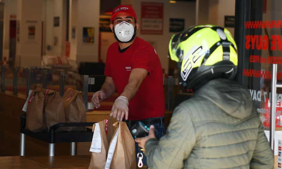 A Five Guys worker brings food out to delivery drivers in Clapham