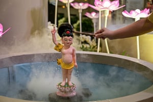 A Buddhist pours water over a statue of Prince Siddhartha Gautama