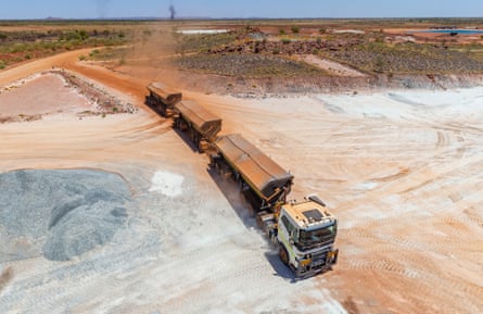 aerial view of huge truck and trailers in dusty, dry landscape of white salt-like rocks and orange sand
