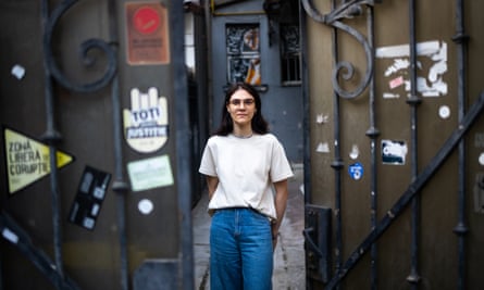 A young woman stands inside a pair of large gates that are covered in stickers
