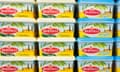 Close-up of a stack of yellow Bertolli olive oil spread tubs on a shelf