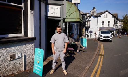 Wideshot of man stood looking at camera in T.shirt with street and blue sky behind