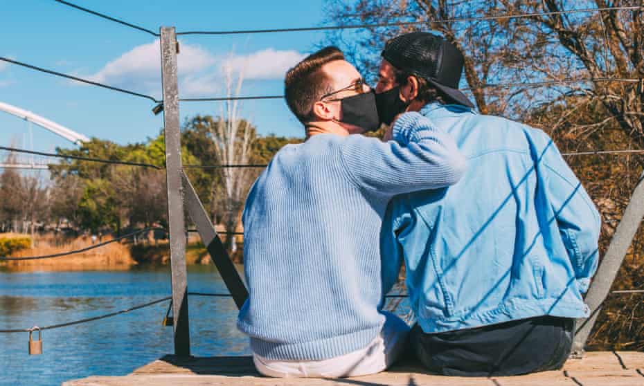 A gat couple kiss with face masks on