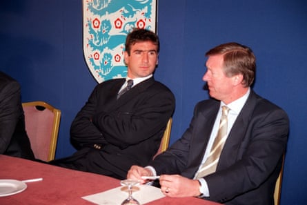 Two men in suits sit at a table with the FA logo behind them.