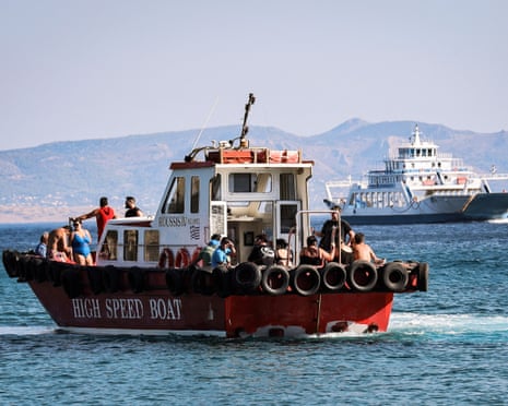 People sit on a boat as they are evacuated during a wildfire in the island of Salamis, near Athens, Greece.
