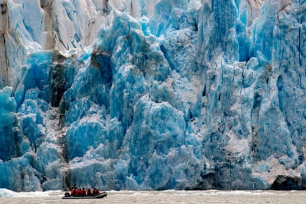 People in a dinghy pass a huge glacier