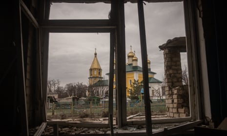 Una iglesia parcialmente destruida se ve desde la ventana de una escuela destruida en Kupiansk, en la región de Kharkiv.