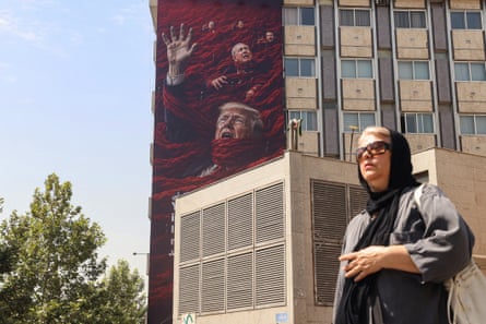 A woman walks past a billboard erected on the side of a large apartment building