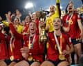Spain's players celebrate their 2023 Women's World Cup win, one holding up the gold trophy