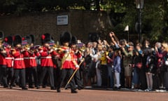 Crowds watch the band of the Grenadier Guards march towards the Mall and Buckingham Palace.