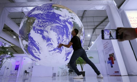 A Cop27 attendee poses for a picture near a model earth during the climate summit in Sharm el-Sheikh, Egypt.