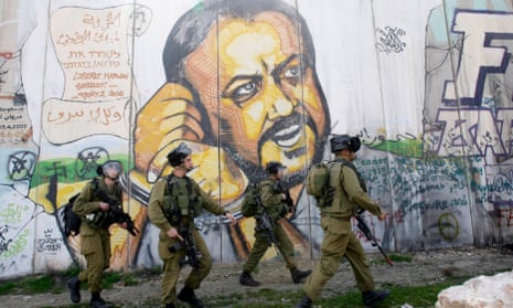 Israeli soldiers patrol in the West Bank city of Ramallah with a mural showing Marwan Barghouti.