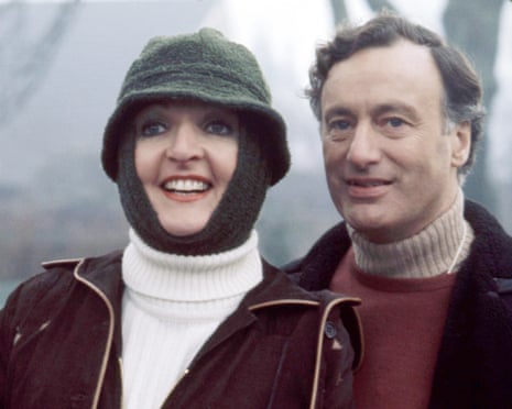 Close up of Penelope Keith wearing a strange winter hat/scarf contraption and white polo neck and jacket with Paul Eddington in polo neck - both smiling off camera