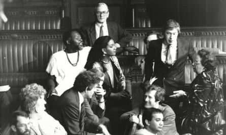 A group of a dozen MPs, male and female, sitting and standing in the House of Commons.