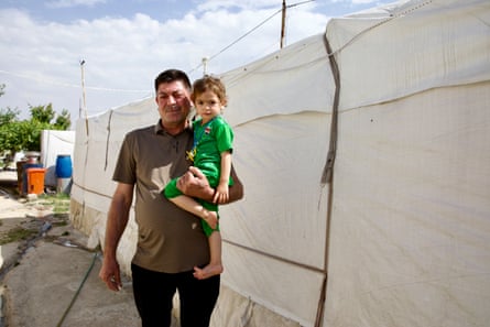 A Middle Eastern man holds a small child in one arm