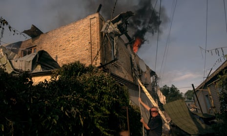 A man tries to extinguish a fire at a residential house that was hit during Russian shelling in Kherson, Ukraine.