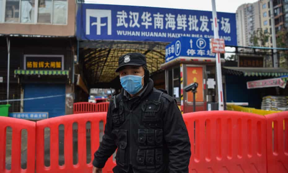 A police officer stands guard outside the shuttered Huanan seafood market in Wuhan.