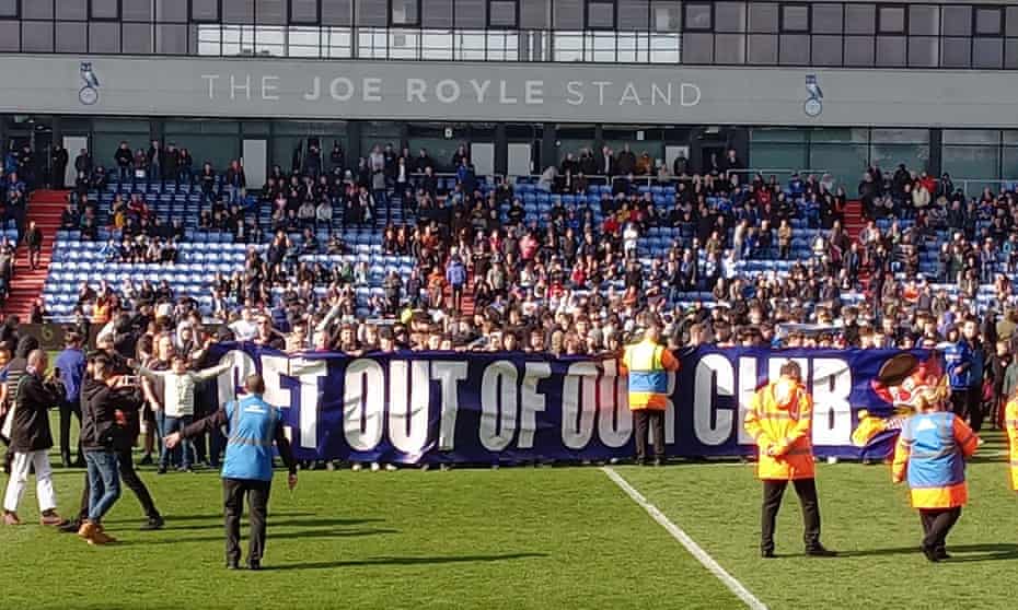 Oldham fans invade the pitch and hold up a banner aimed at owner Abdallah Lemsagam.