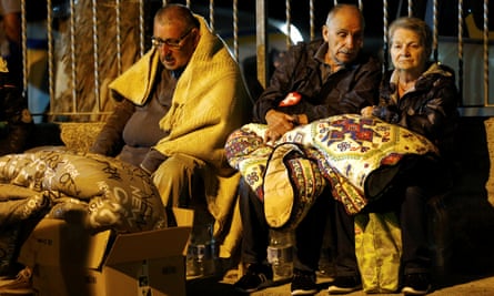 People keep warm under blankets after the earthquake in Amatrice.