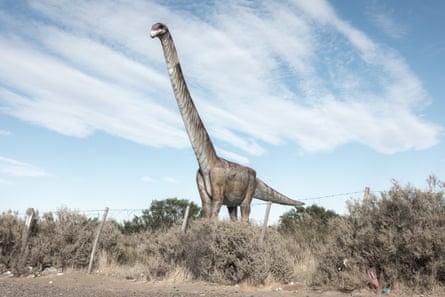 Replica of a colossal dinosaur with a long neck standing in scrubland