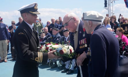 Cdr Glenn Hinson presents a wreath to veterans Alec Penstone, right, and Harry Birdsall as part of a service in memory of the soldiers, sailors and airmen who did not make it ashore, from the ferry Mont St-Michel, off the coast of Normandy, France