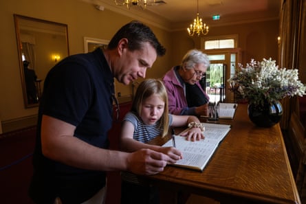 Matthew Walker and his seven-year-old daughter Emily sign a condolence book at Government House in Perth