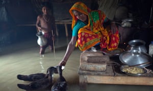 A woman feeds hens in her house in the flood-hit Kurigram district of Bangladesh