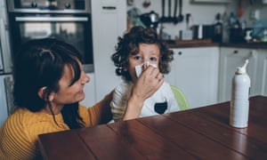 Mother helping son to blow his nose at home